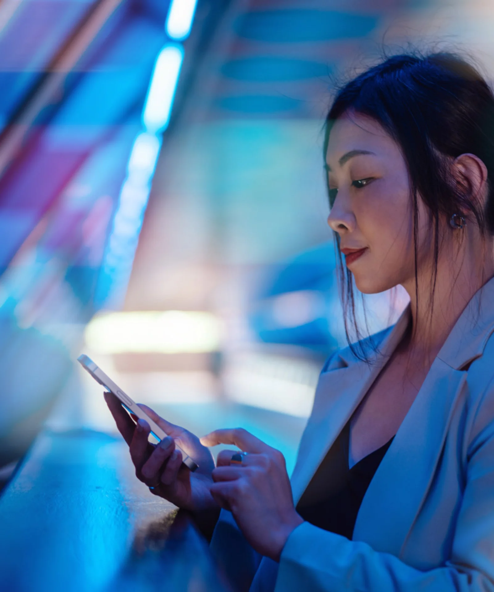 Digital Banking in a Connected World A woman in a business suit uses her smartphone, surrounded by vibrant, abstract digital colours, symbolising the connected and dynamic nature of digital banking.