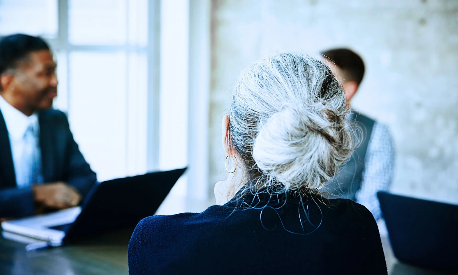Key Visual Investor Relations Key visual for investor relations showing a diverse business meeting with a focus on a woman with grey hair in a bun.
