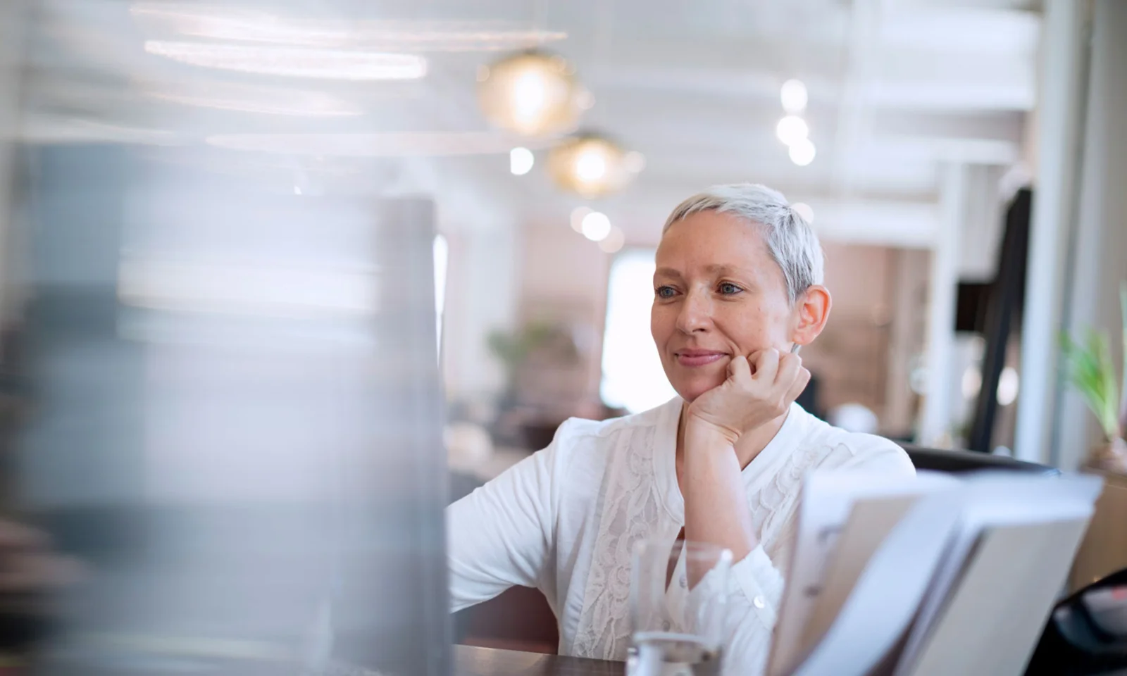 Healthcare Manufacturer Transforms HR with AI Chatbot Smiling professional woman working at her desk in an office, representing the transformation of HR with AI chatbots.
