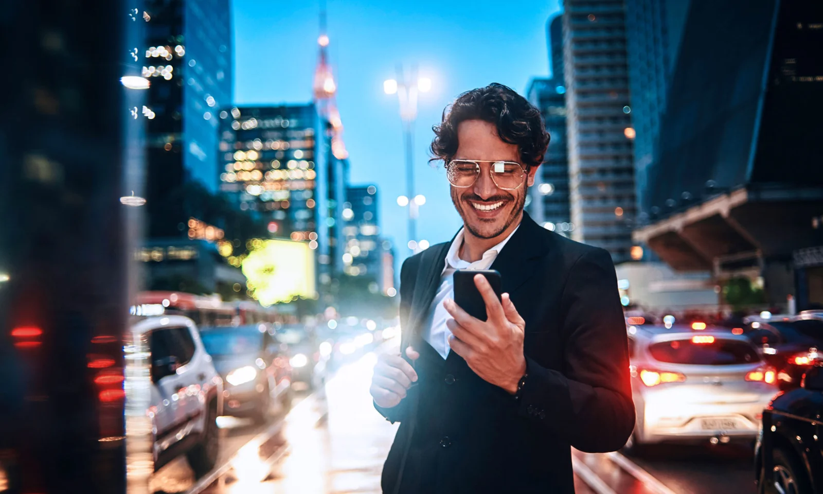 Business Professional Engaging with Mobile Banking in a Modern Cityscape A smiling business professional interacts with a smartphone in a bustling city at night, symbolising the future of digital banking.